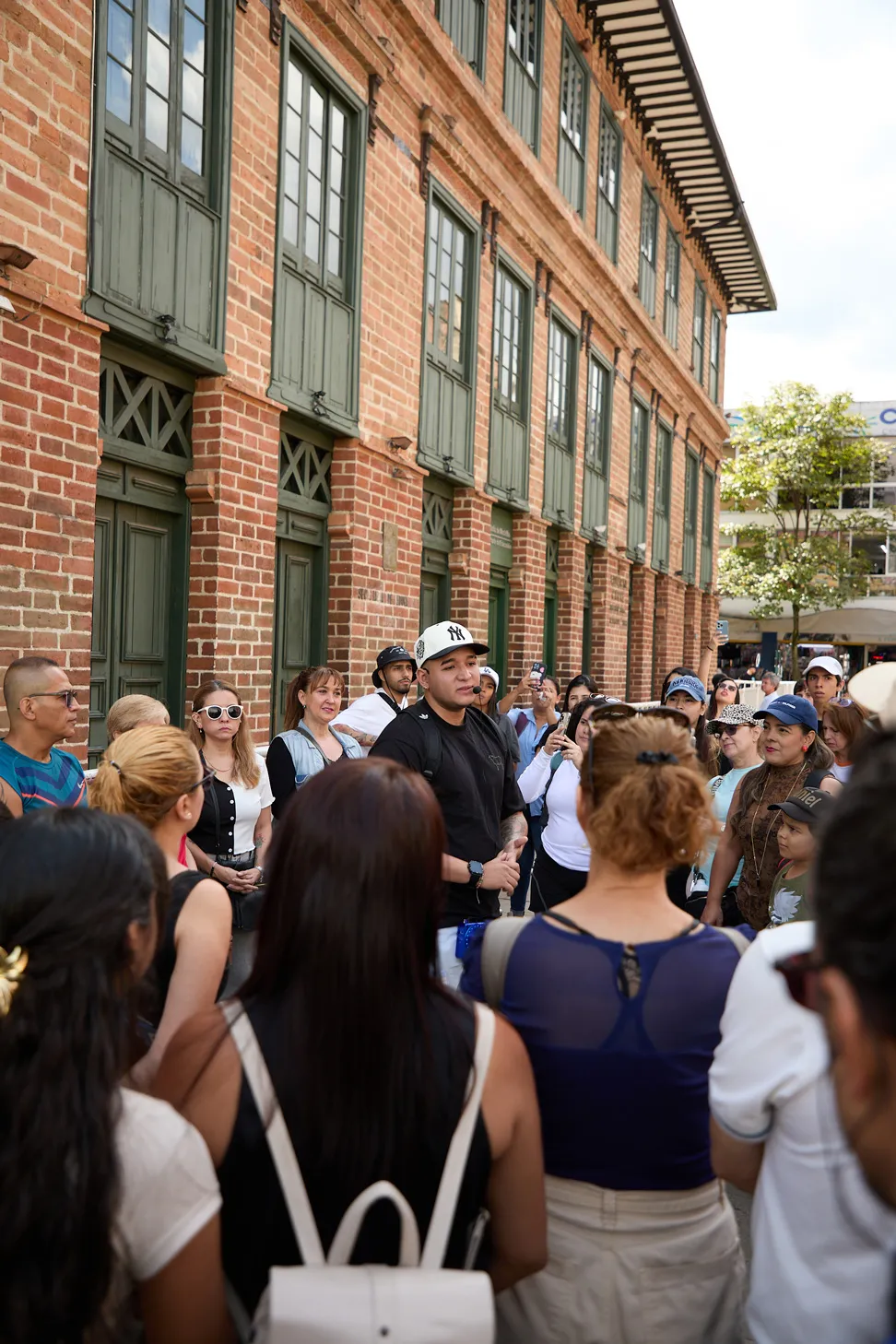 City Tour por el centro histórico de Medellín – Colombia en tus ojos Tours Guía explicando la historia de Medellín a un grupo de turistas frente al Palacio Nacional