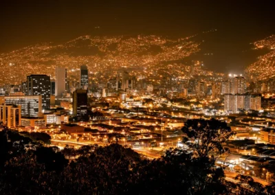 Vista nocturna del centro de Medellín con luces de edificios y barrios desde un mirador