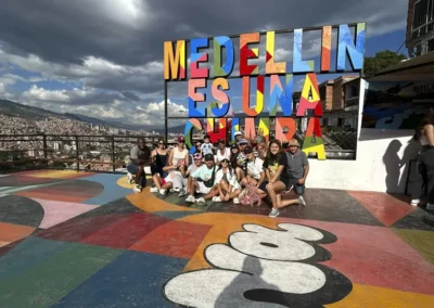 Grupo de turistas en la Comuna 13 con el letrero Medellín es una chimba