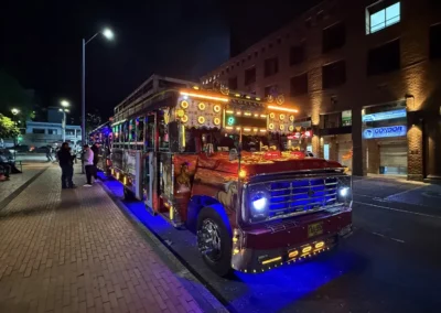 Chiva Rumbera del tour nocturno de Medellín estacionada en una calle con luces y ambiente festivo