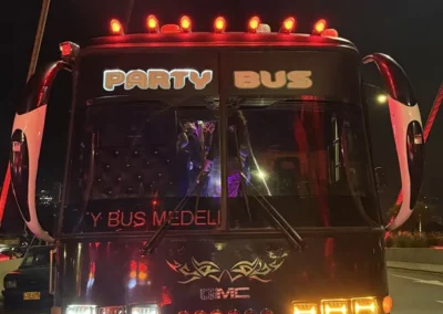 Vista frontal del Party Bus Medellín iluminado durante el recorrido nocturno del tour